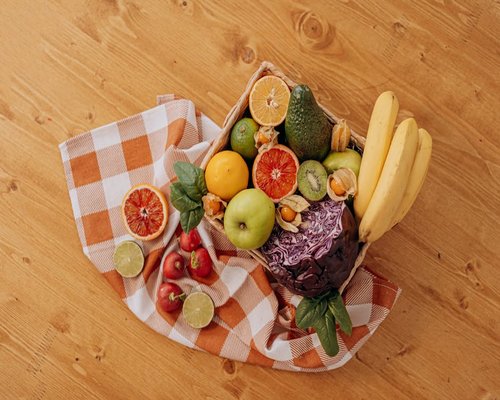 Basket of fresh tropical fruits on a wooden table
